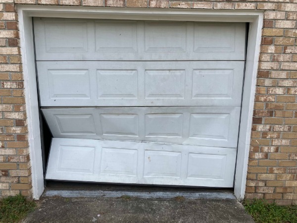 Severely damaged/buckled white garage door